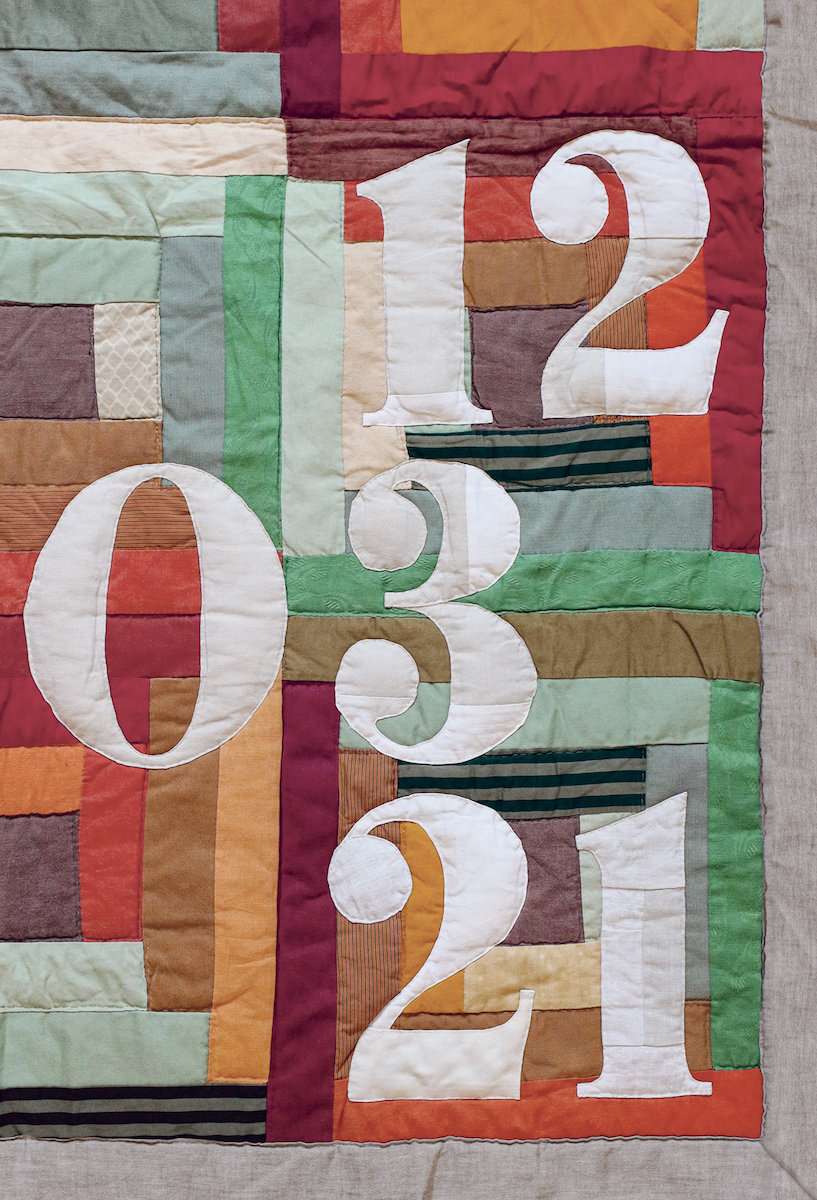 Détail de patchwork orange et vert avec la date de naissance en appliqué, atelier Pénélope Westberg